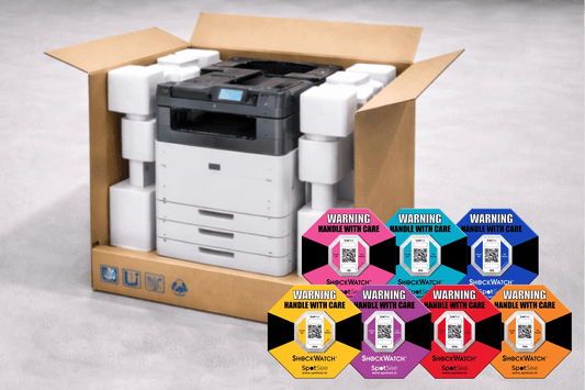 ShockWatch 2 QR impact indicators in all seven sensitivities — 5G pink, 10G teal, 15G blue, 25G yellow, 37G purple, 50G red and 75G orange — shown with a boxed printer ready for shipping